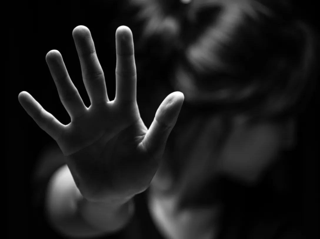 Person raising a hand in a protective gesture