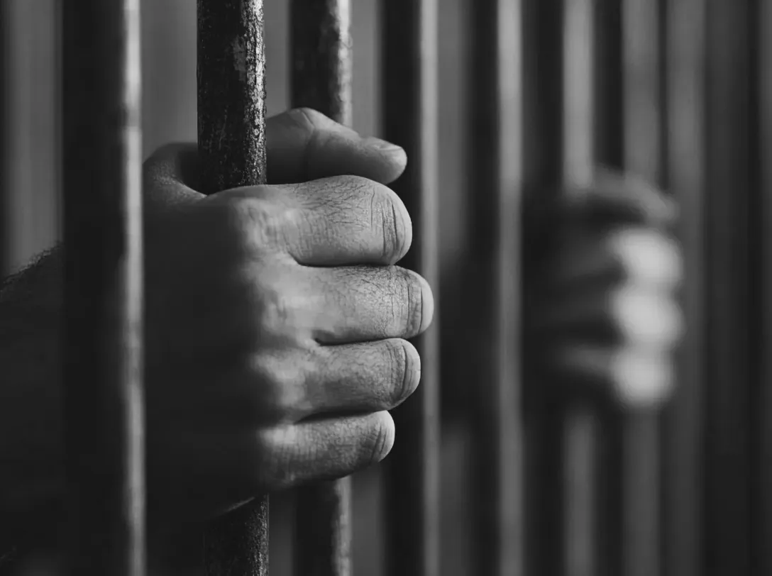 Hands gripping prison bars
